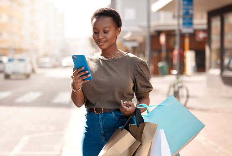 Posh dark-skinned woman shopping smiles at her new upgraded mobile phone