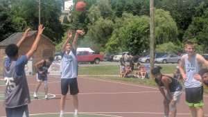 young men playing basketball on an outdoor court