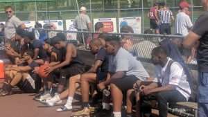 young men playing a basketball game on an outside court