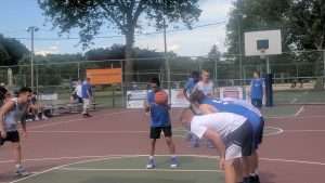 young men playing a basketball game on an outside court