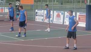 young men playing a basketball game on an outside court