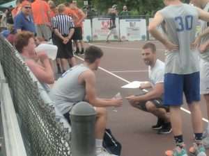 young men playing a basketball game on an outside court