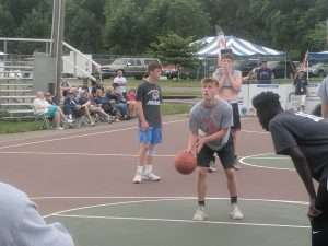 young men playing a basketball game on an outside court