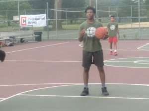 young men playing a basketball game on an outside court
