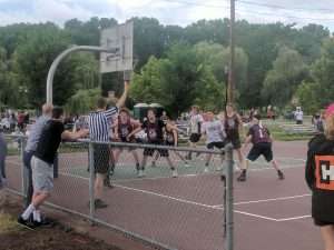 young men playing a basketball game on an outside court