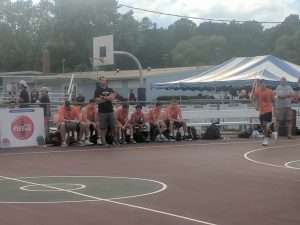 young men sitting on the bench at a basketball game on an outside court