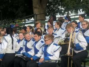 band students waiting to perform while sitting in stadium seats