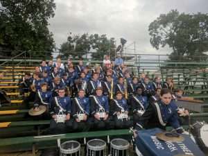 Band posing for a picture in stadium bleachers