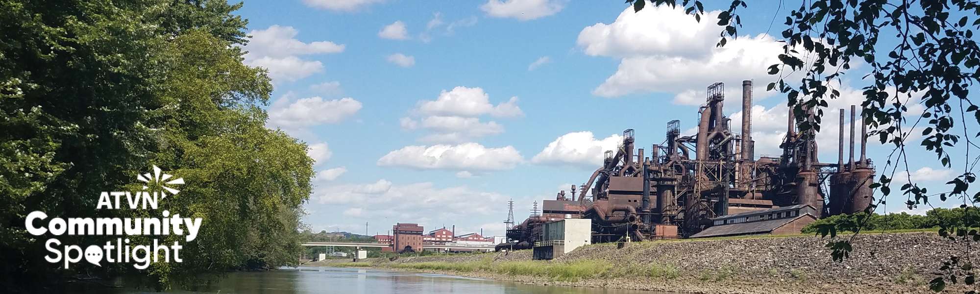 ATVN community spotlight banner with manufacturing building near a river