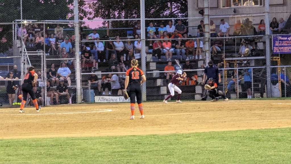 action shot of girl throwing a pitch at high school softball game