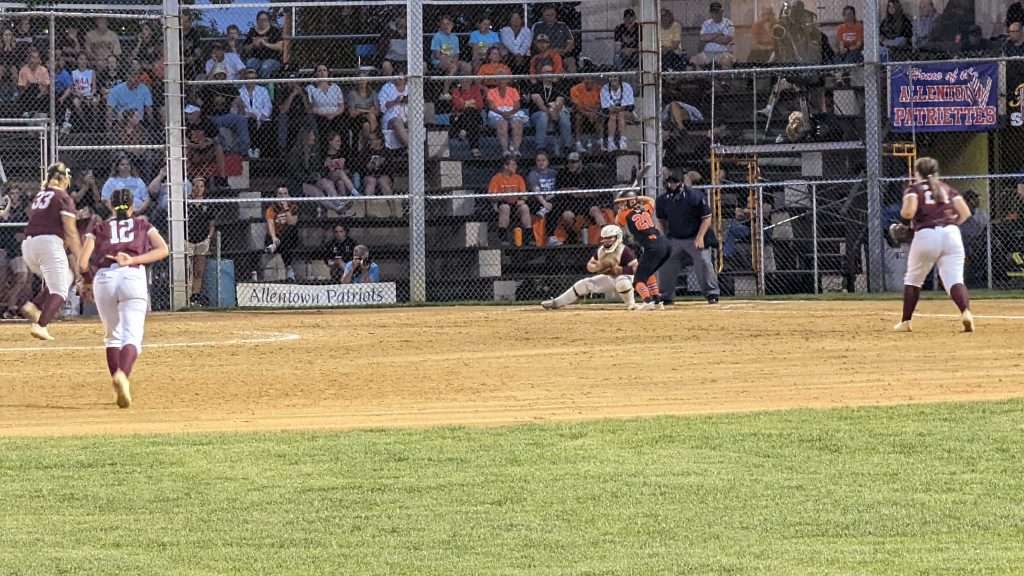 action shot of girl throwing a pitch at high school softball game