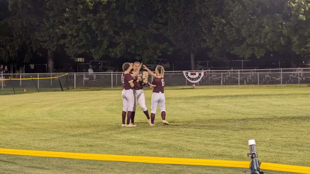 action shot of girls high fiving at softball game