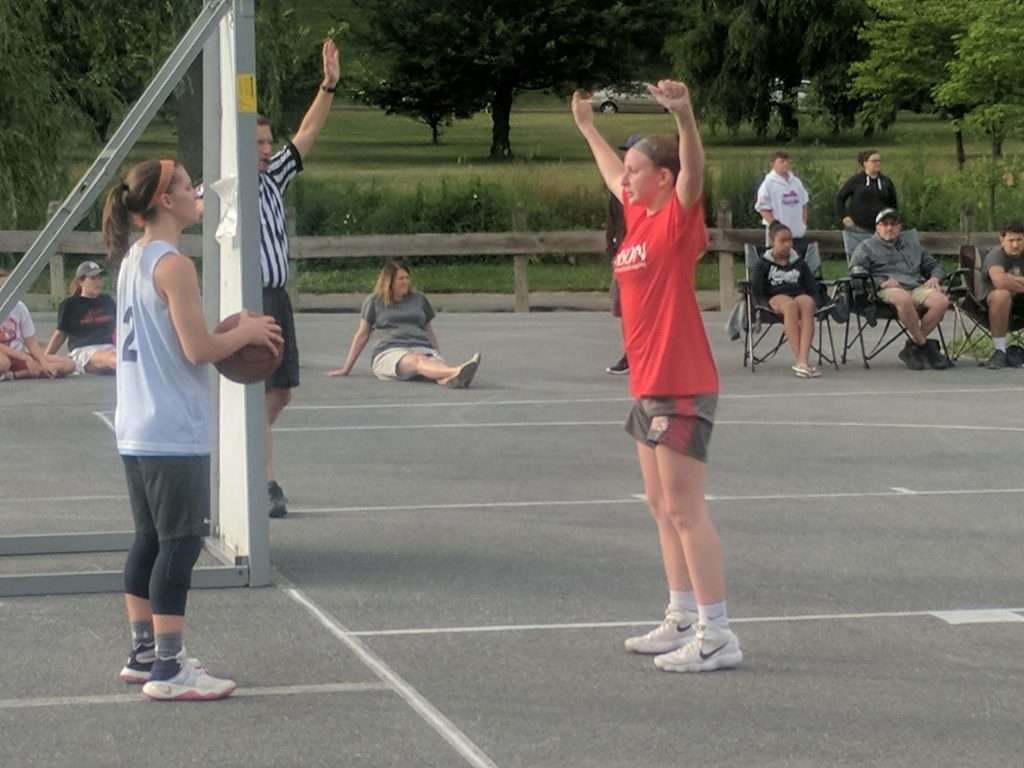 two high school girls playing basketball on an outdoor court