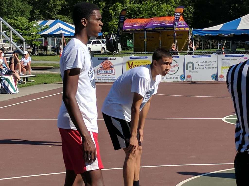 high school boy bent over tired from playing outdoor basketball game