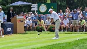 man golfing with green rolex clock in background