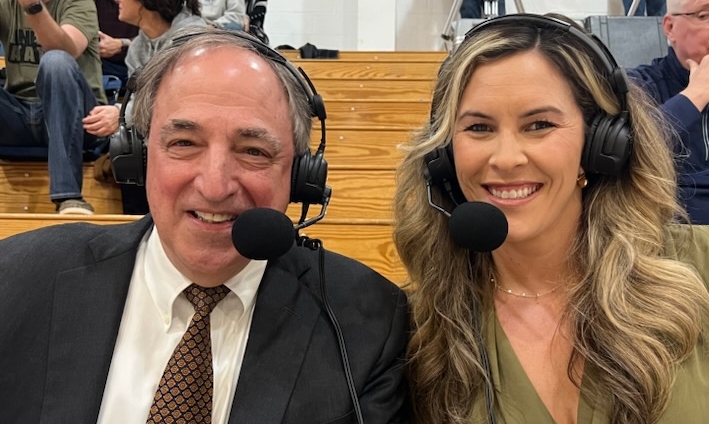 one older man and one middle aged woman sports announcers smiling at camera