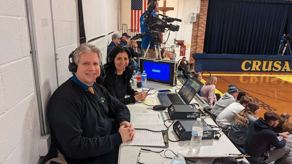 one middle aged mand and middle aged woman sports announcers for ATVN smiling at the camera