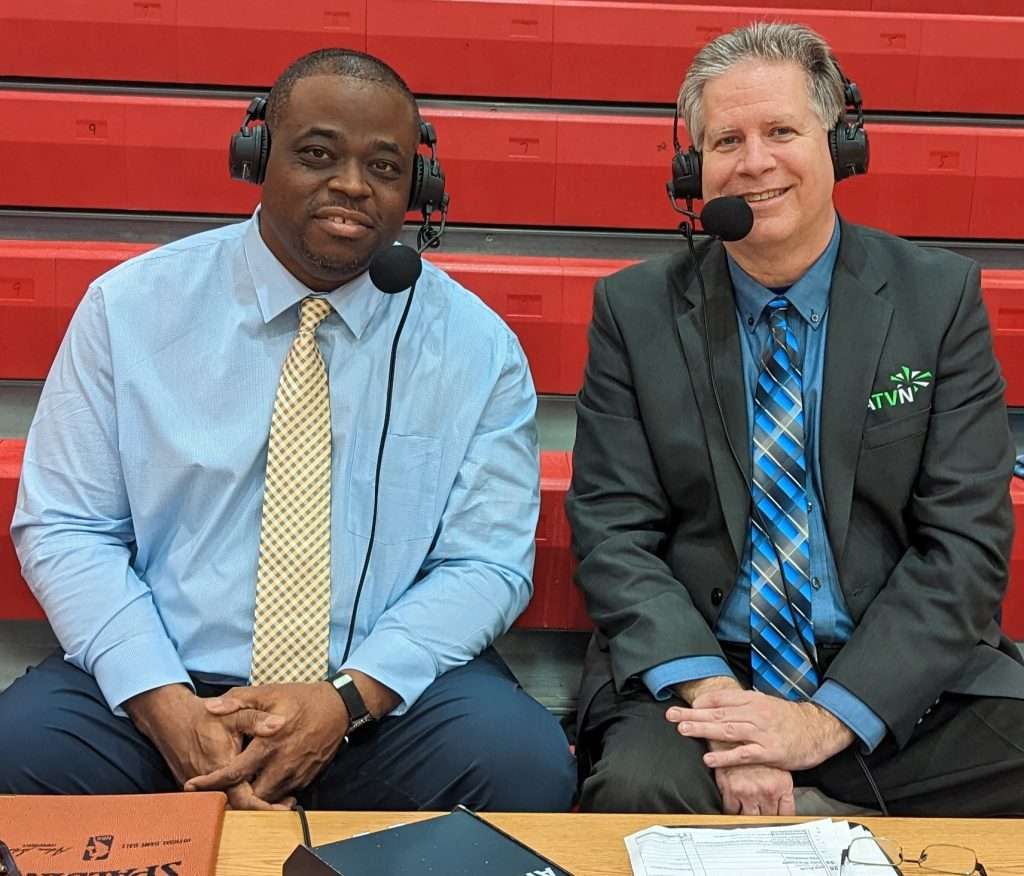 two middle aged ATVN men sports announcers smiling at camera