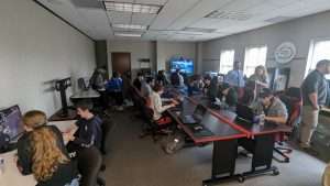 people surrounding high school gamers who are competing on their computers