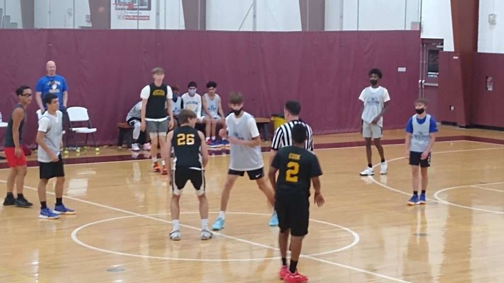 High school basketball game action shot of players reaching for the ball during the tipoff