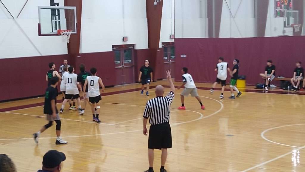 High school basketball game action shot of players shooting a three pointer