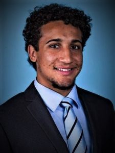 Profile image of Jake Young wearing a blue suit shirt, black suit jacket and striped tie