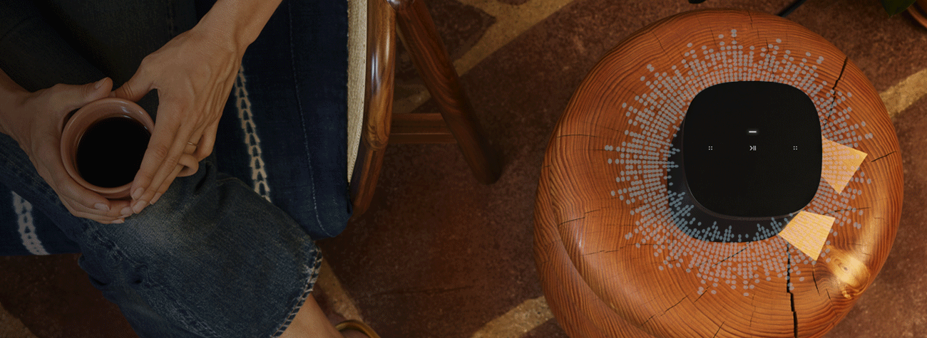 sonos on a side table and a woman drinking coffee next to it