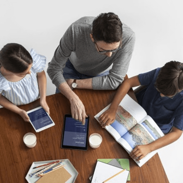 top angle view of a dad and kids around a table each working on their own devices