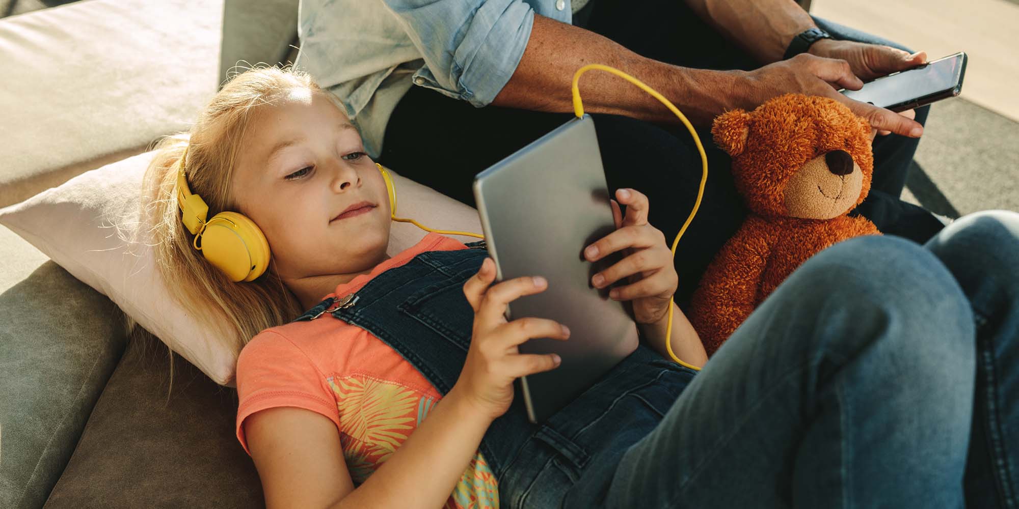 girl with tablet wearing headphones watching tv