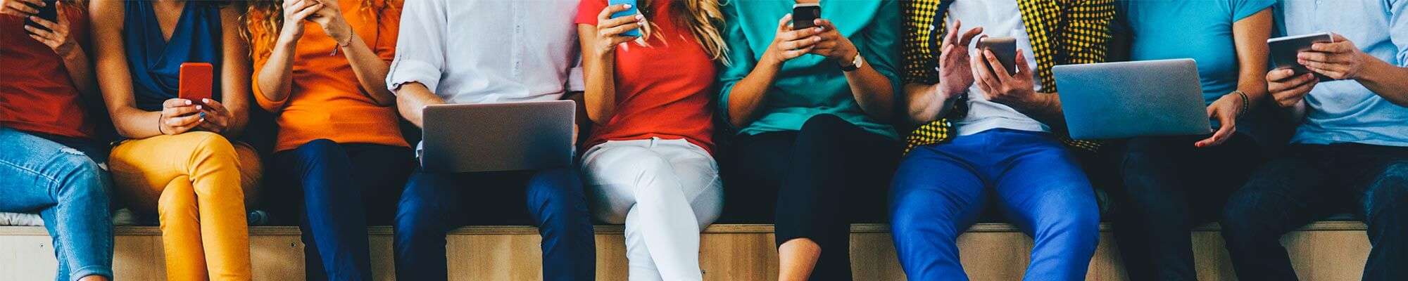 People sitting on bench with devices