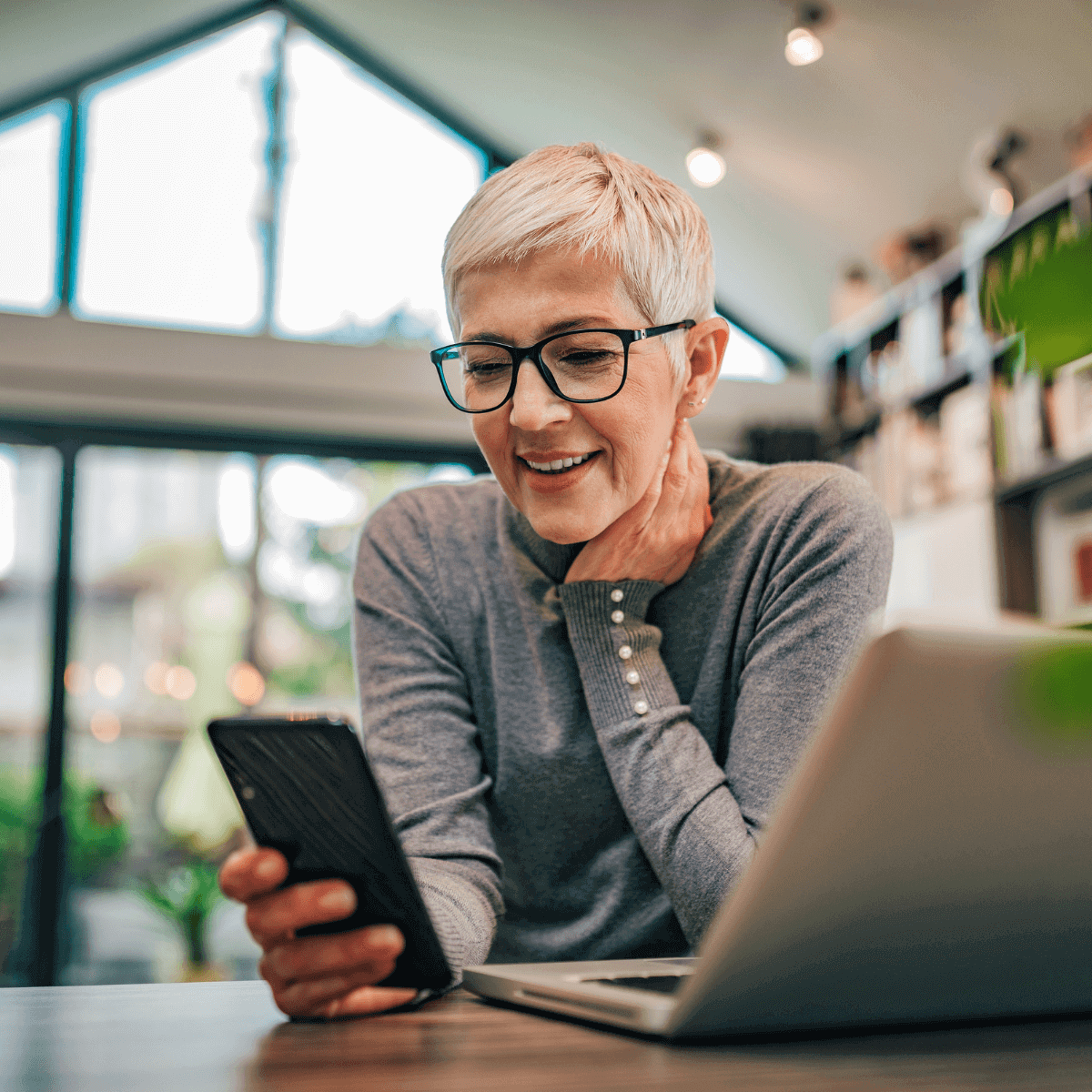 Woman at home on smart phone with laptop