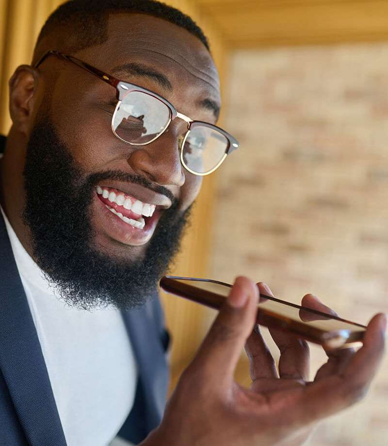 A black man in eyeglasses recording a voice message