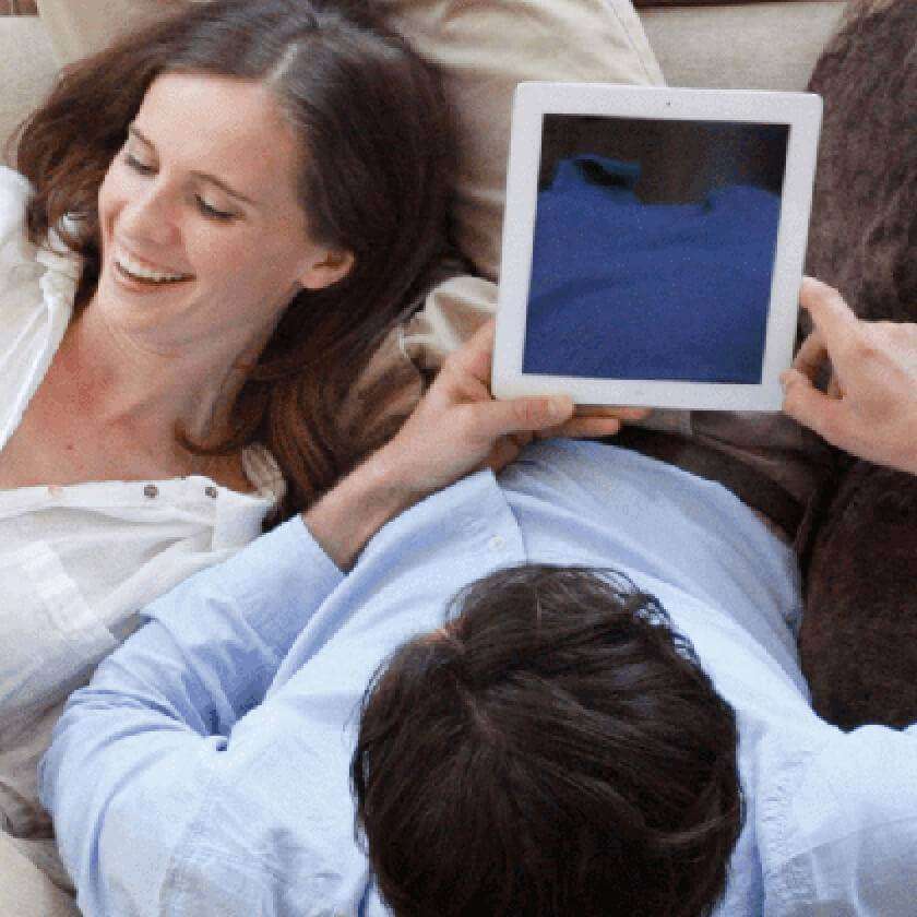 couple on couch looking at tablets