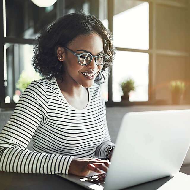 woman with glasses working on laptop