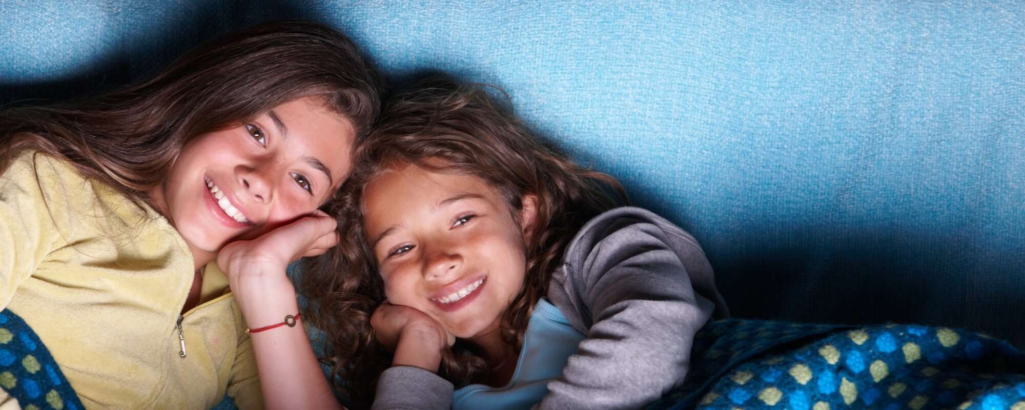 two young girls watching tv at night