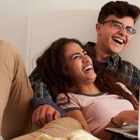 two young adults laughing at laptop