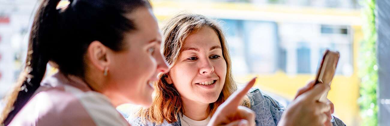 Women at a cafe look at mobile phone