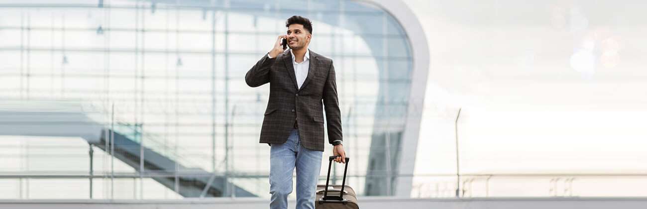 Man outside airport uses mobile phone while traveling