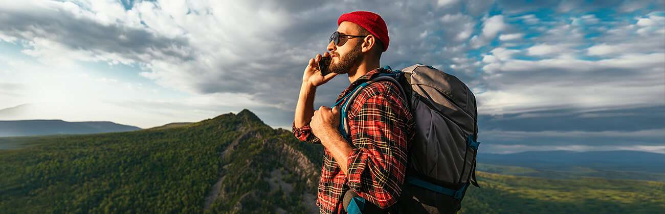 Man uses mobile phone while hiking in mountain wilderness
