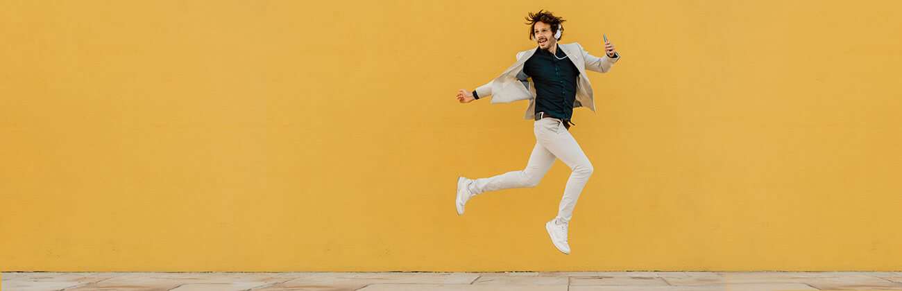 Young guy is jumping with joy to save data as he streams music