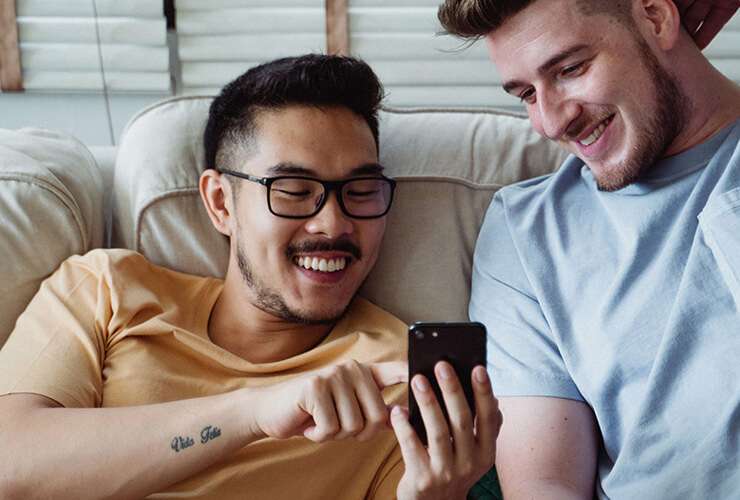 Two casually dressed young guys smile at something on a mobile phone