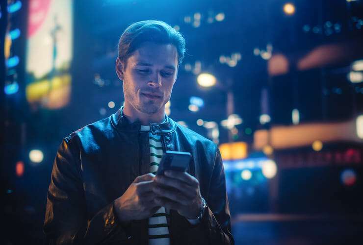 Guy in city nighttime setting uses mobile phone