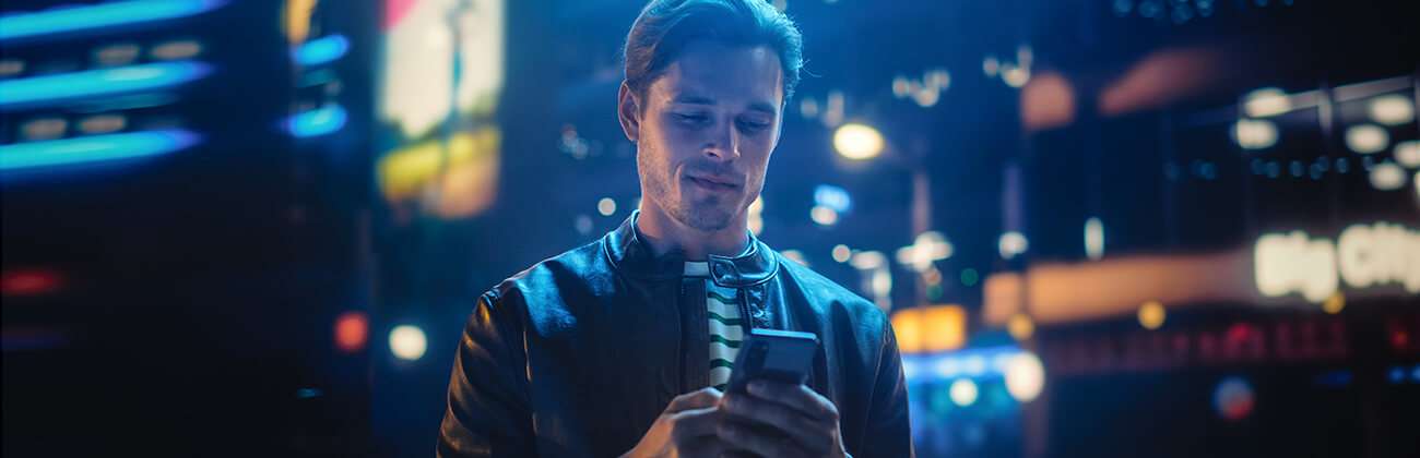 Guy in city nighttime setting uses mobile phone