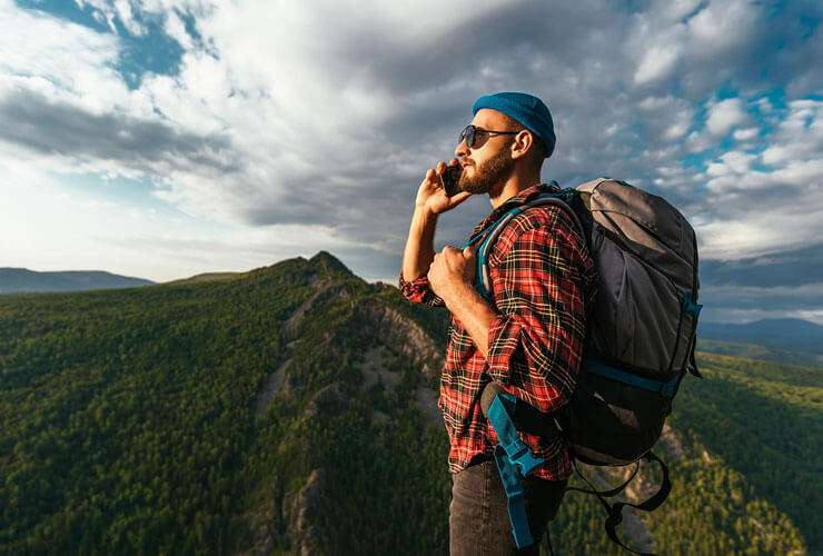 Man uses mobile phone while hiking in wilderness mountains