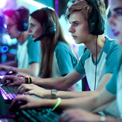 row of players on laptops and headphones compete at multiplayer gaming