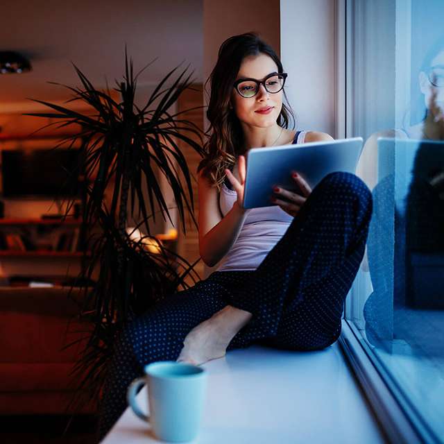 Woman in casual attire uses tablet at home