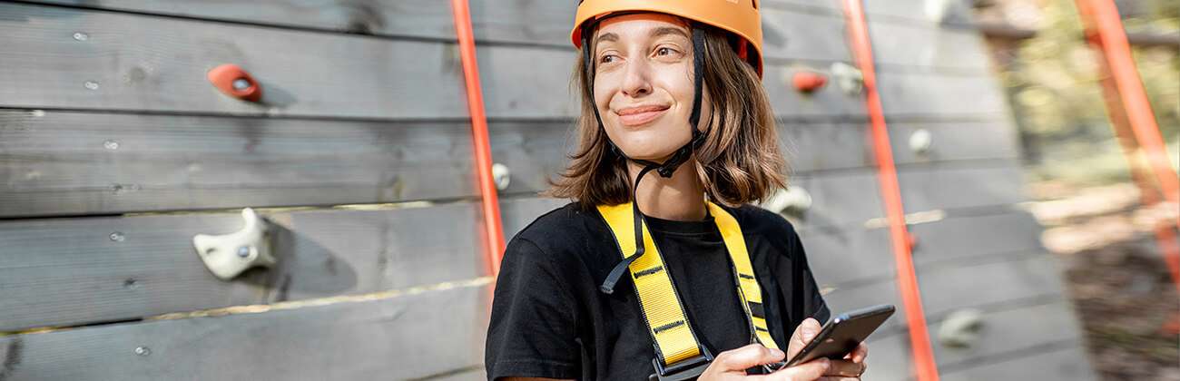 Woman with phone at outdoor climbing wall
