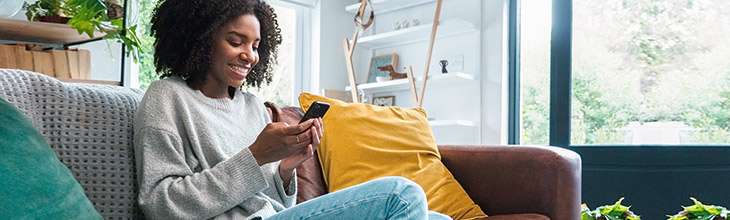 African american woman on sofa checks phone settings