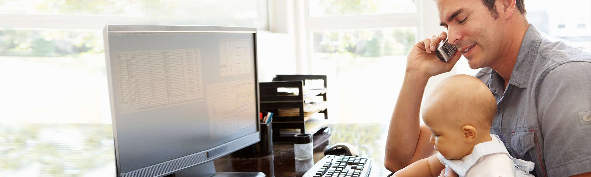 Hispanic man on landline desk phone holding his baby