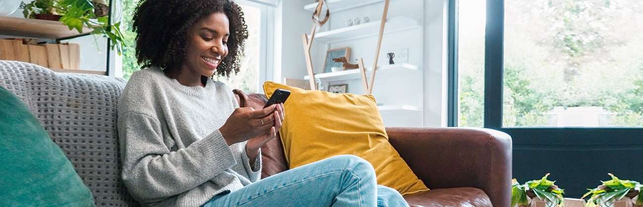 African American woman on sofa checks phone settings